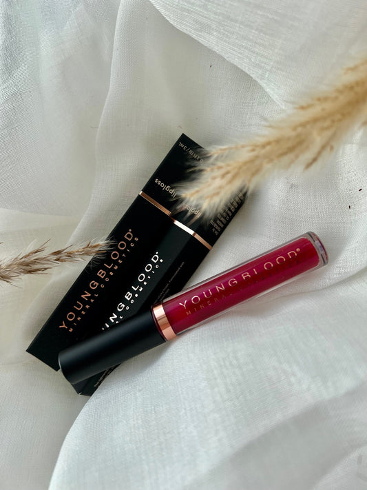 Young Blood Lipgloss i farven Flame. Luksuriøs lipgloss med skinnende finish, der giver læberne et fyldigt og blødt udseende. Den livlige Flame-nuance tilfører et varmt, intenst og iøjnefaldende udtryk til læberne. Produktet vises i Young Bloods elegante emballage, der afspejler mærkets høje kvalitet og eksklusive formuleringer